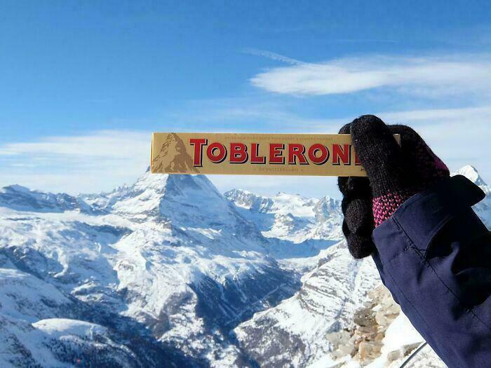 Amazing photos: gloved hand holds Toblerone bar with snowy Matterhorn and alpine peaks under blue sky