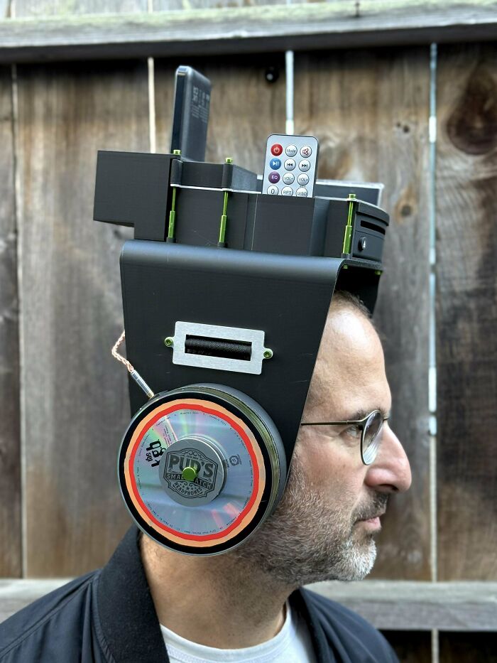 Man wearing a DIY disaster headset with a remote and CD attached, showcasing a creative but flawed homemade design.