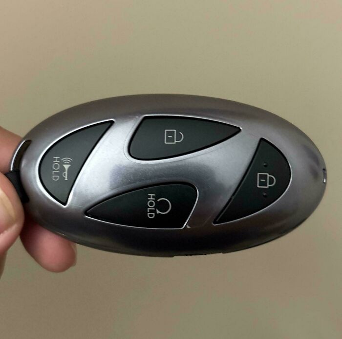 Sleek car key fob with smart button design held in hand, showcasing innovative and cool designer functionality.