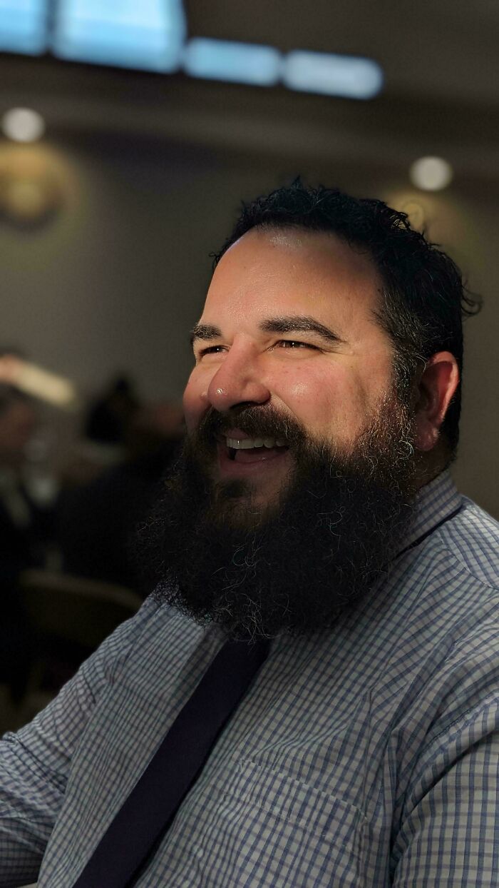 Bearded man smiling warmly in soft light, capturing the essence of accidental Renaissance photo style.