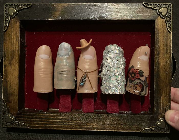 Five creative handmade finger replicas with unique designs displayed in a vintage wooden frame on red velvet.