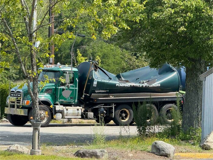 A green Mack truck with a severely dented tank, showing an expensive accident or fail.