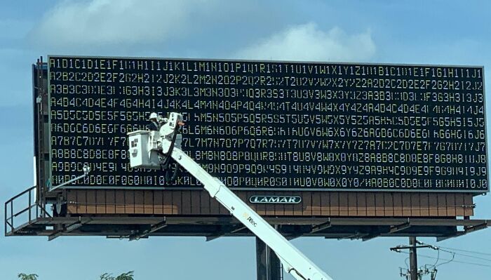 Billboard with digital numbers and letters being serviced, illustrating advertising fails and unattainable body portrayal concept.