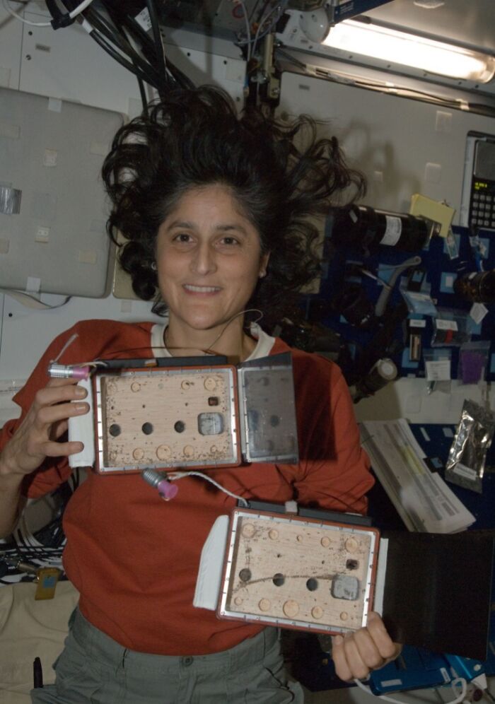 Female astronaut floating in a spacecraft holding scientific instruments related to headlines that rocked the world in 2025.