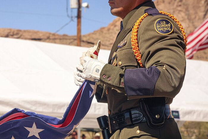 U.S. Border Patrol agent in uniform folding a flag during a ceremonial event, highlighting impactful 2025 headlines.