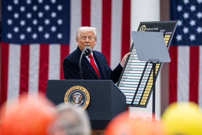 Former U.S. president speaking at podium with American flag backdrop, holding a chart, capturing headlines that rocked 2025.