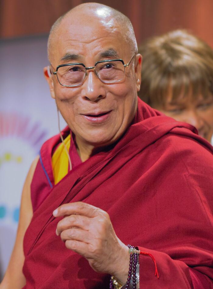 Elderly man in red robes and glasses smiling warmly, representing headlines that rocked the world in 2025.