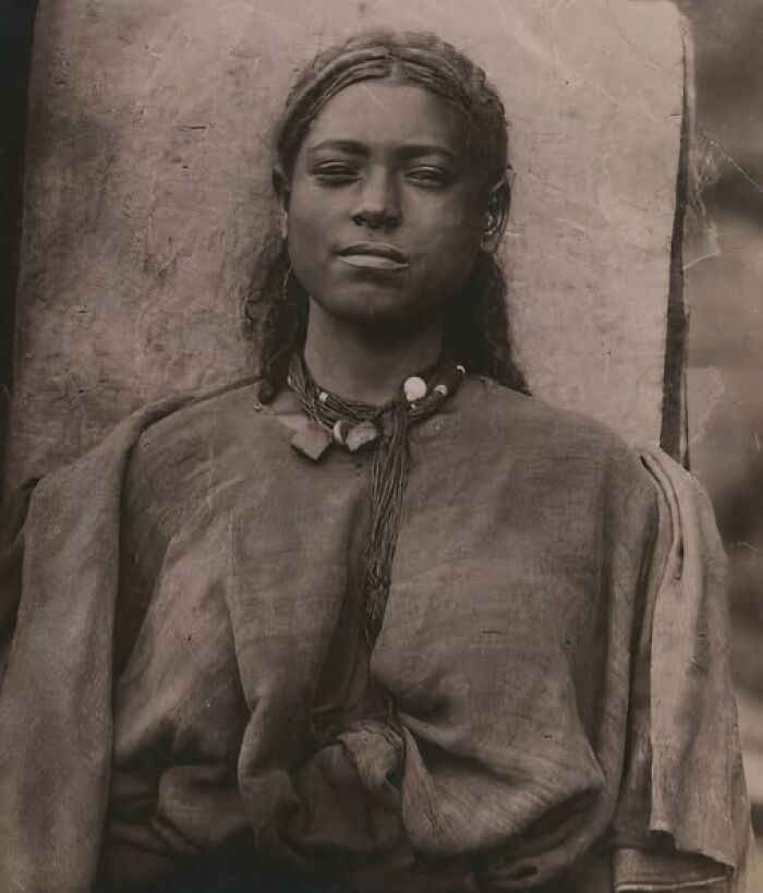 Portrait of a 19th century young woman wearing traditional clothing and jewelry in an invaluable historic photo.