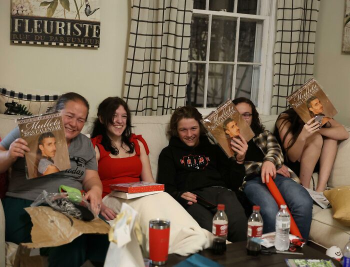 Group of people sitting on a couch holding matching calendars showing a rare coincidence captured in a candid photo.