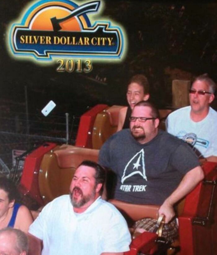Roller coaster photo capturing a rare coincidence of a falling phone and riders' surprised expressions.