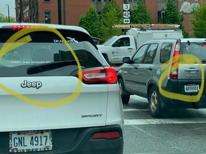 Two cars in traffic show matching Wayward-themed stickers and license plates, a rare coincidence in a city setting.