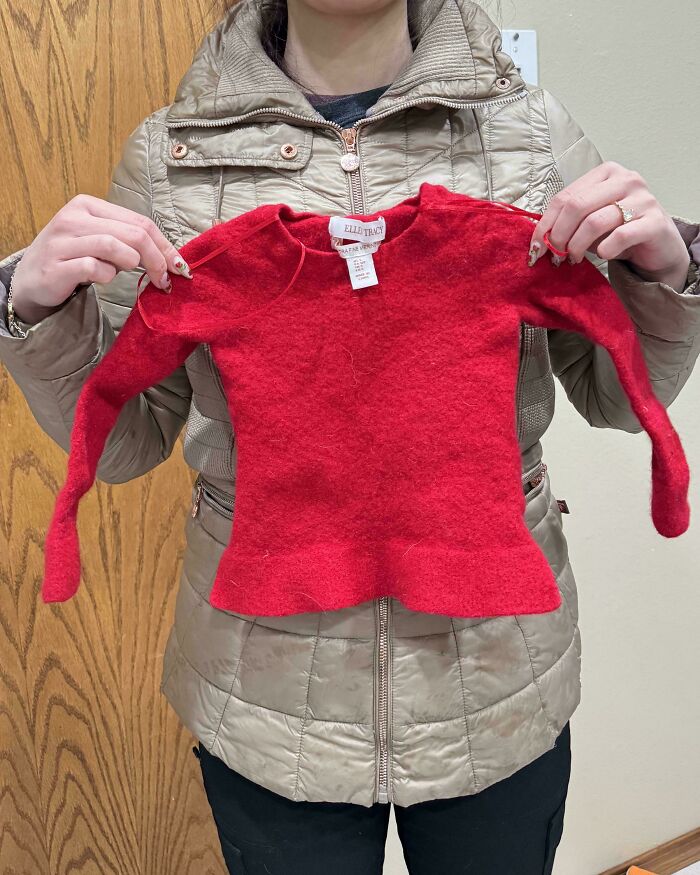 Person holding a shrunken red sweater as a funny way people learned their lesson with clothing care mistakes.