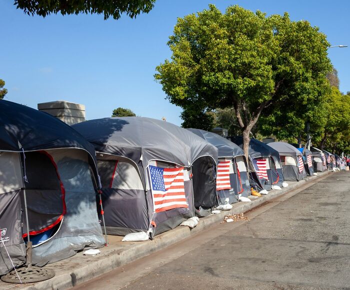Row of tents with American flags along a city street, highlighting a scene that makes you wonder about the point of no return.