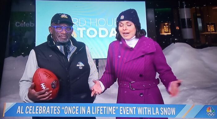 Two news anchors standing outside in heavy snow, discussing a rare weather event that makes you wonder about the point of no return.