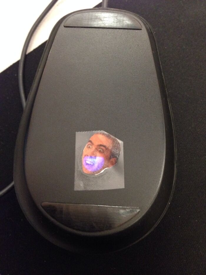 Computer mouse with a funny face sticker over the sensor, showing a humorous way people learned their lesson.