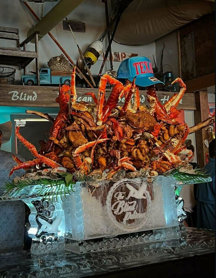 Large seafood dish with crab legs and shellfish piled high on an ice tray at a restaurant, showcasing unusual dishes.