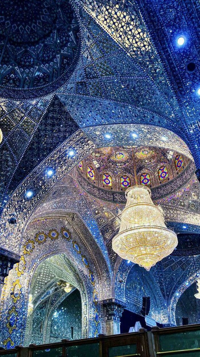 An example of beautiful architecture with a stunning, ornate blue and gold ceiling and a large chandelier.
