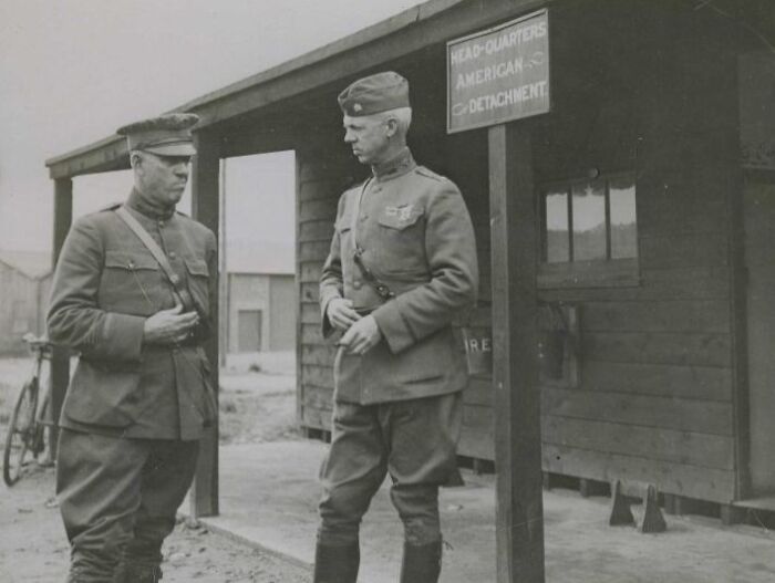 Two WWI soldiers standing and talking outside the American detachment headquarters showing daily life beyond the WWI trenches.
