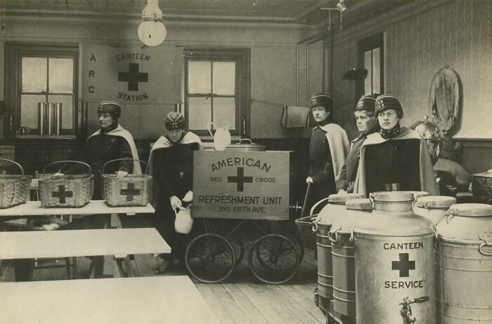 American Red Cross canteen volunteers serving refreshments, revealing daily life beyond the WWI trenches in a small indoor station.