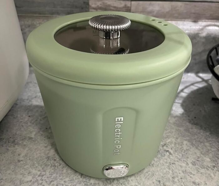 Compact green electric pot with glass lid on kitchen counter, an essential dorm kitchen survival guide item.