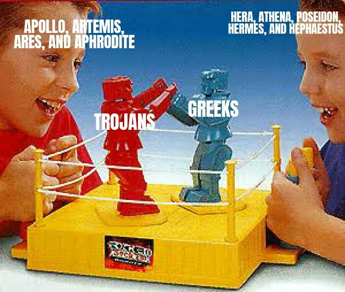 Two kids playing with red and blue rock-em-sock-em robots labeled with Greek mythology figures and Trojans.