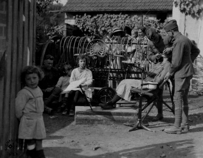 Children and soldiers interacting outdoors, showing daily life beyond the WWI trenches in a black and white historical photo.