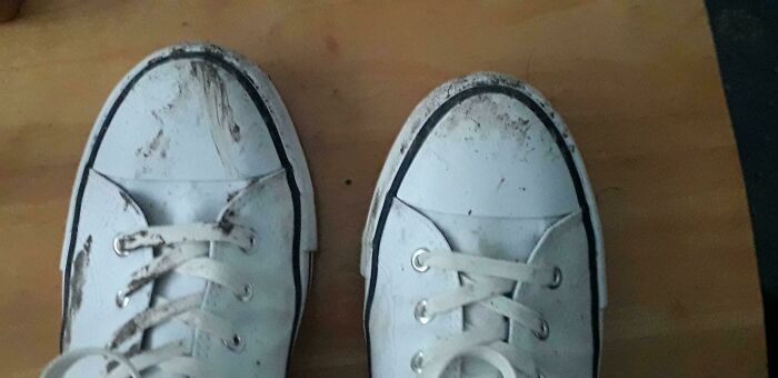 Worn-out white sneakers with visible dirt showing a funny way people learned their lesson through experience.