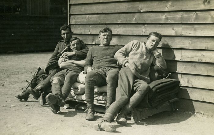 Four WWI soldiers relaxing outside wooden barracks, showing daily life beyond the WWI trenches during downtime.