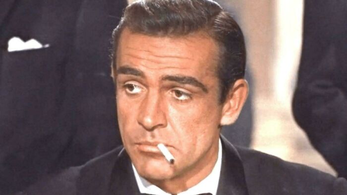 Actor in a classic movie scene with cigarette, highlighting bad movie details discussed by an online group.