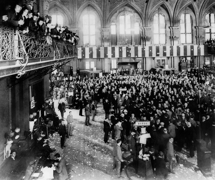 Crowd gathered in a grand hall with high arched windows, showcasing a gripping picture of 1800s America life and events.