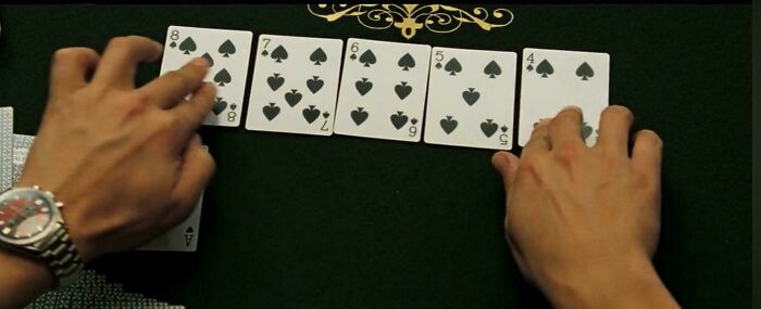 Hands arranging playing cards on a green table, illustrating a confusing bad movie detail from an online group.
