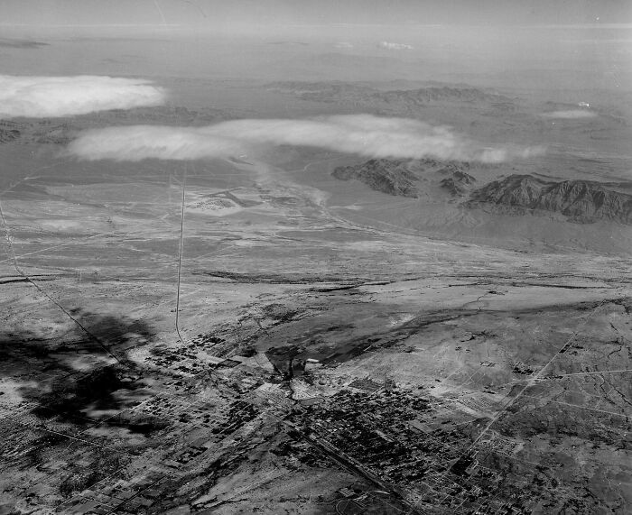 Aerial view of early Vegas development showcasing historic landscape and surrounding mountains during its birth era.