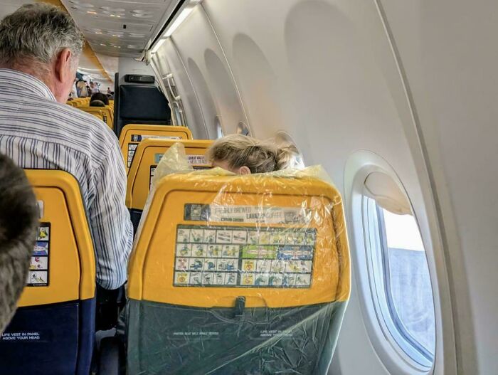Passenger wrapped in plastic on airplane seat, showing lack of care about rules and etiquette in public transport.
