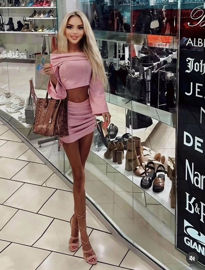 Young woman in a pink outfit posing in a shopping mall with distorted long legs showing Instagram vs reality effects.