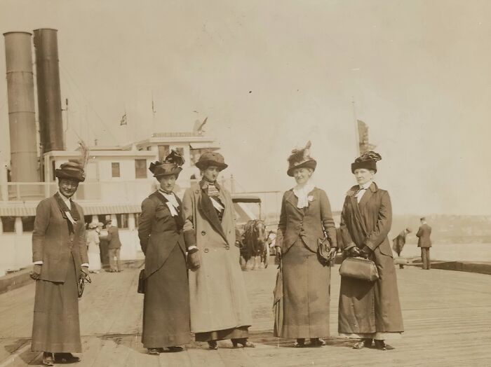 Five women in early 20th century attire standing on a dock, representing powerful photos of women in suffrage era.