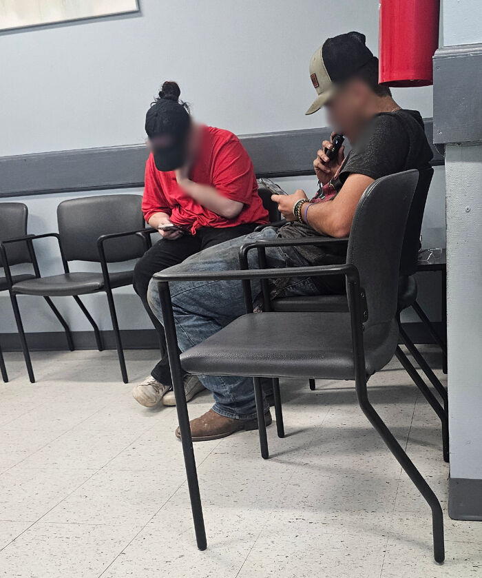 Two people sitting closely in a waiting room, ignoring social distancing rules in this infuriating photo showing lack of etiquette.