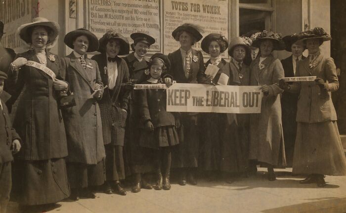 Group of women in 20th century suffrage era holding banners advocating voting rights during the suffrage movement.