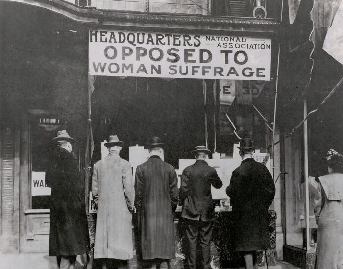 Men standing in front of a National Association headquarters opposed to woman suffrage during the 20th century suffrage era.