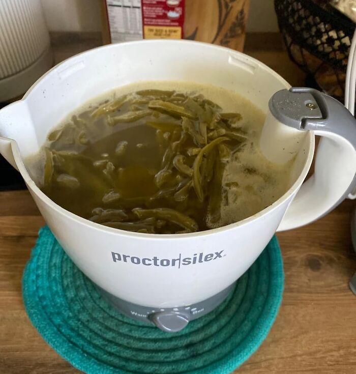 Electric kettle with green beans boiling in water, a practical dorm kitchen essential for easy meal preparation.