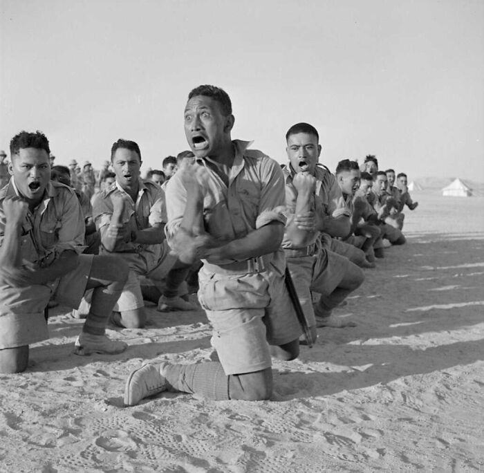 Group of soldiers performing intense training exercise in desert setting in historical photo with strong emotions visible