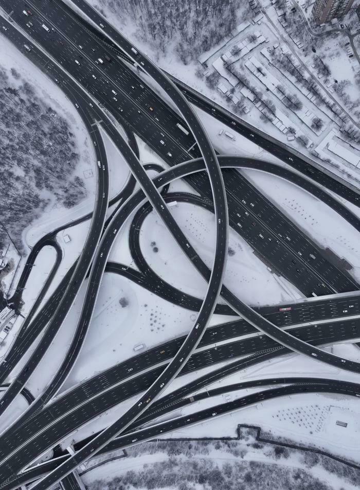 Aerial view of a complex highway interchange covered in snow, showcasing brilliant infrastructure design.