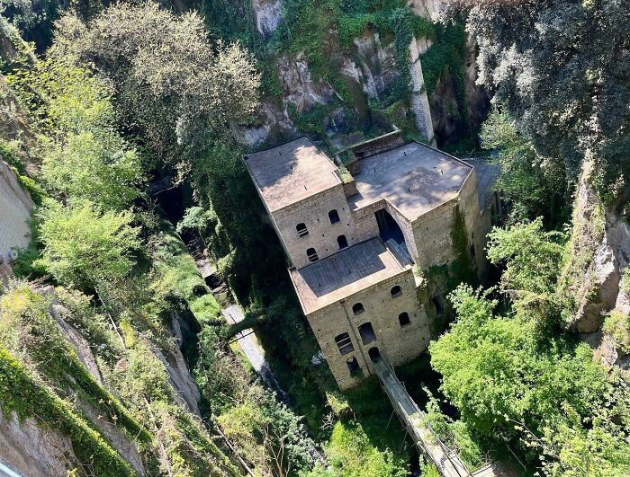 Abandoned building nestled in a lush green valley surrounded by rocky cliffs and dense foliage, a haunting abandoned place.