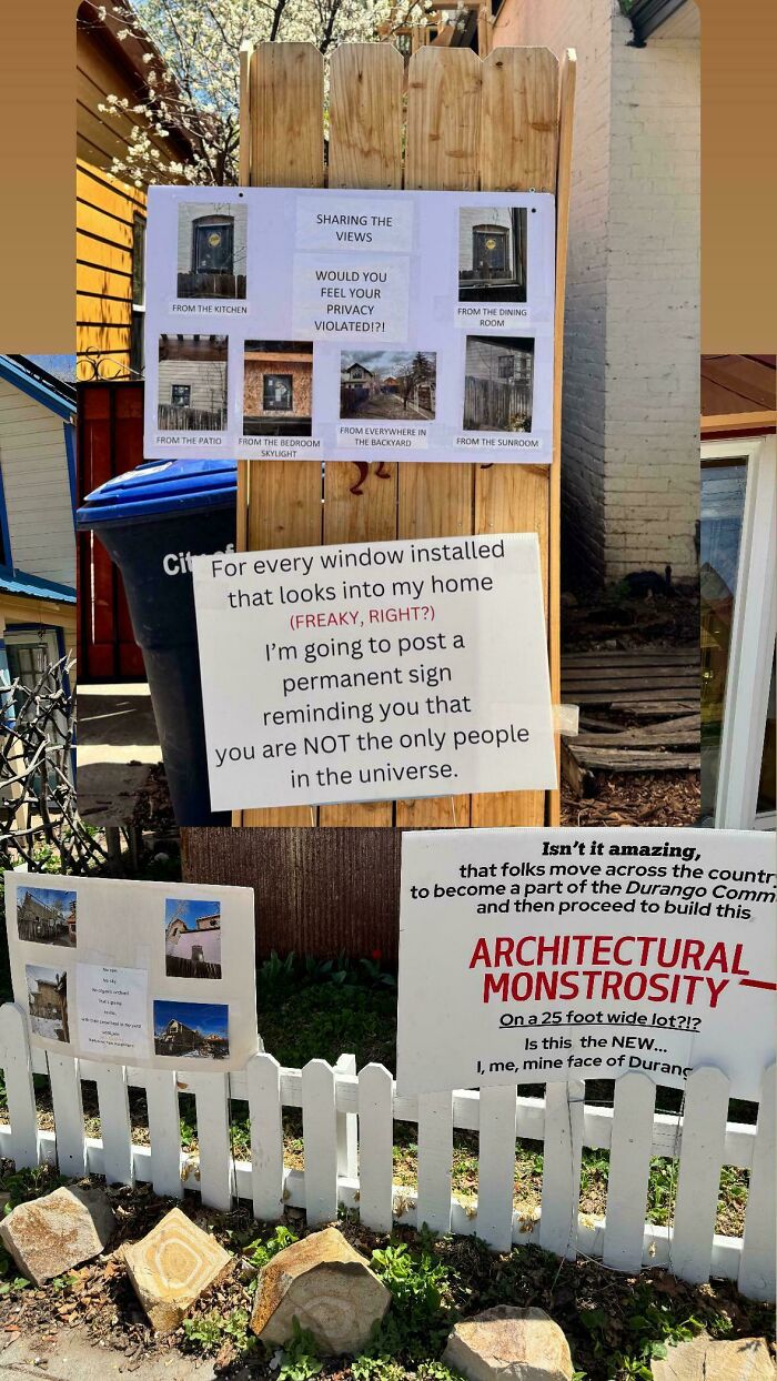 Signs on a wooden fence expressing frustration about privacy violations and architectural monstrosity in a residential neighborhood.