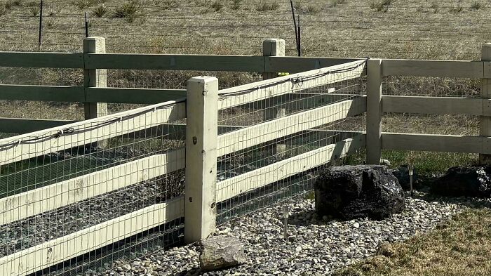 Wooden fence with wire mesh partially broken, showing people with no care about rules and etiquette in an outdoor setting.