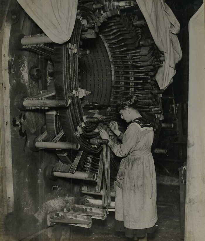 Woman in a historic photo repairing large industrial machinery, showcasing a rare moment from historical photos too wild to forget.