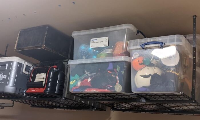 Overhead storage racks holding plastic bins and boxes to hide and organize clutter effectively.