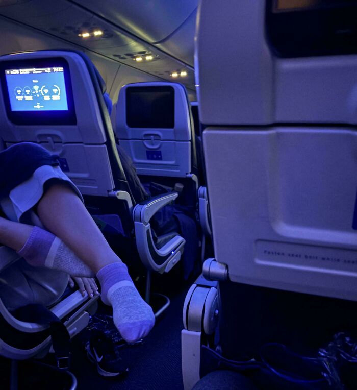 Person resting feet on airplane seat, showing disregard for rules and etiquette in a confined space.