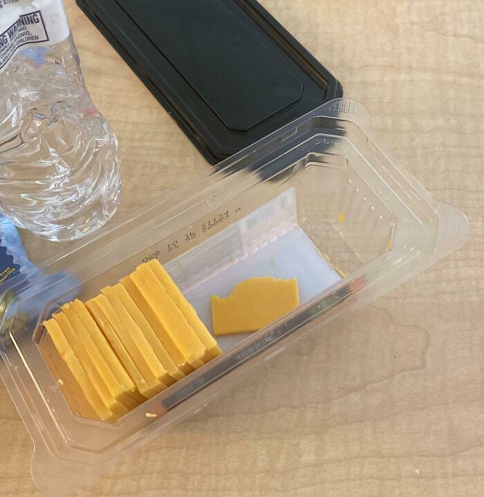 Partially eaten cheese left in a plastic container on a table, showing disregard for rules and etiquette.