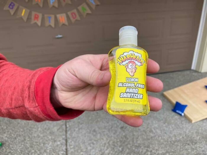 Hand holding a lemon-scented Warheads alcohol-free hand sanitizer, illustrating funny ways people learned their lesson.