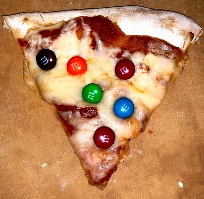 Slice of pizza topped with colorful candy-coated chocolates, an example of food to avoid for physical and mental health.